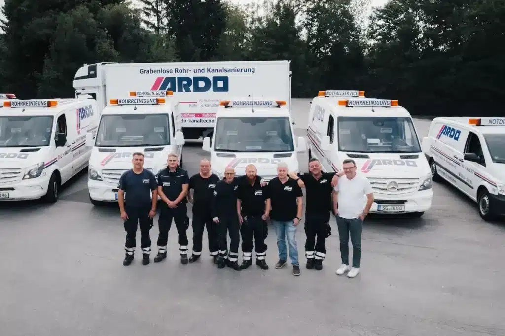 Die Belegschaft von ARDO Abflussreinigung steht vor dem Fuhrpark der Einsatzfahrzeuge